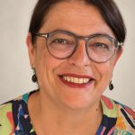 Isabel Serra, thérapeute en chromatothérapie à Auderghem, souriante, en chemisier coloré