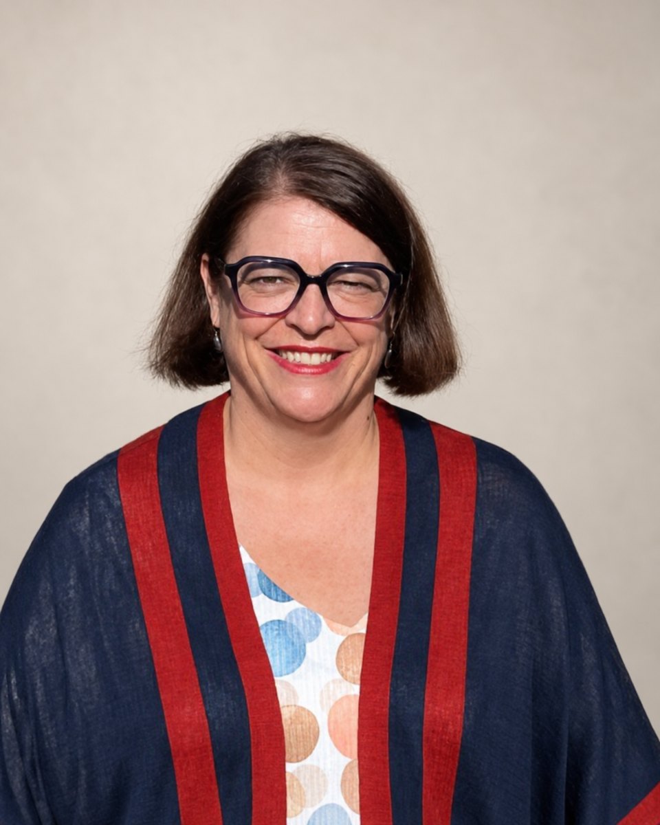 Isabel Serra, thérapeute en chromatothérapie à Bruxelles, souriante, en gilet bleu et rouge